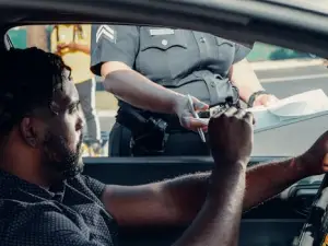 Police officer handing a traffic ticket to a driver during roadside inspection.